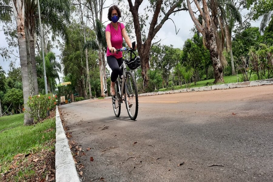 Mulher de máscara pedalando uma bicicleta em parque