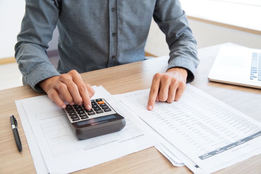 Close-up of unrecognizable man working with financial data. He using calculator and examining document. Financial inspector holding examination. Paperwork or finance concept