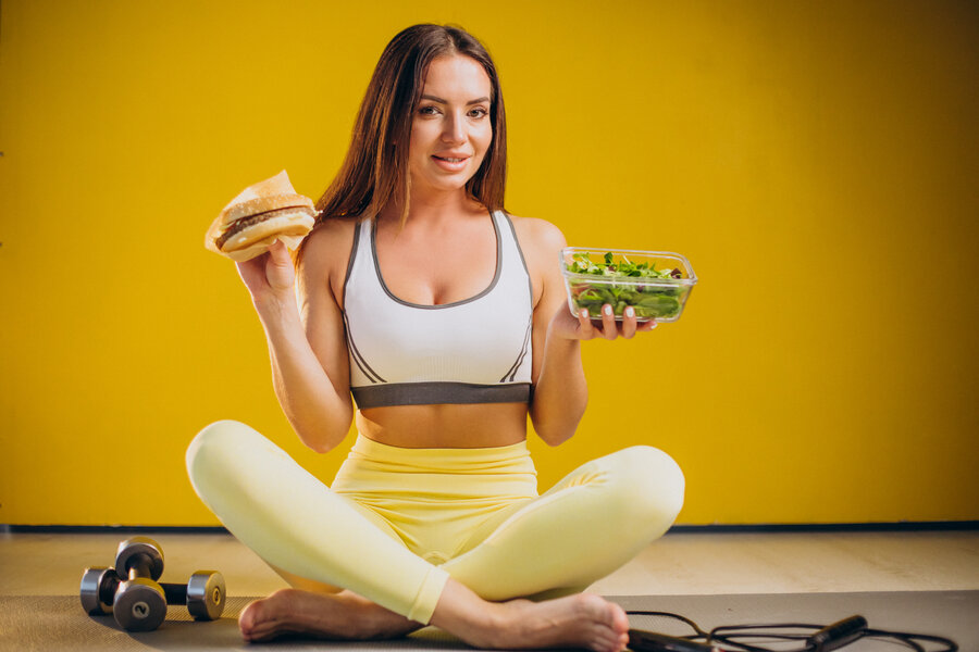 Woman eating salad isolated on yellow background