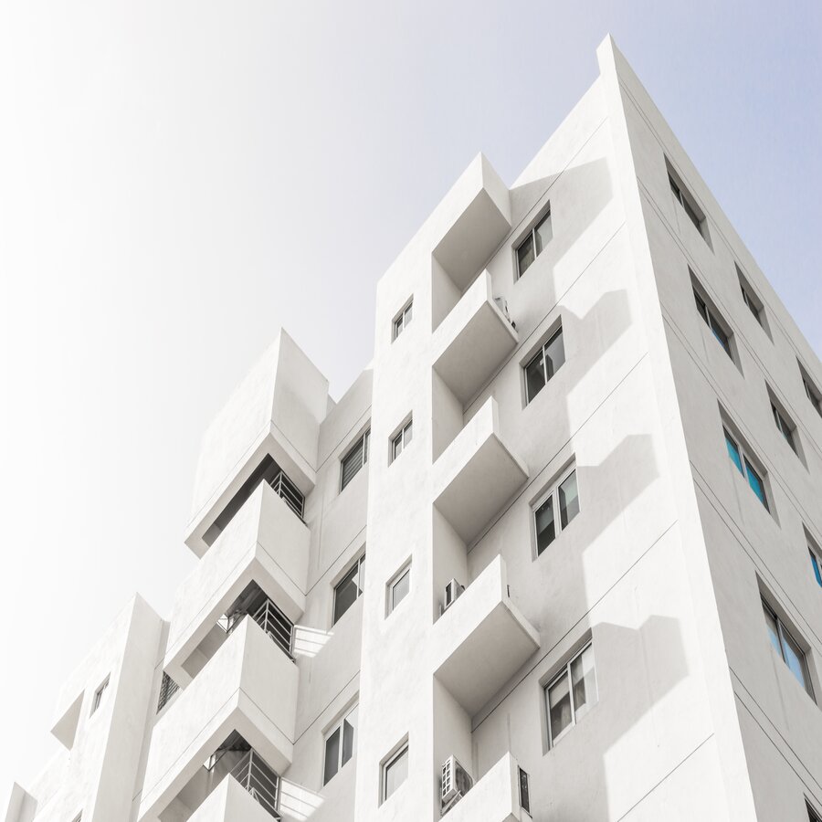 A low angle shot of a facade of a white modern building under a blue clear sky