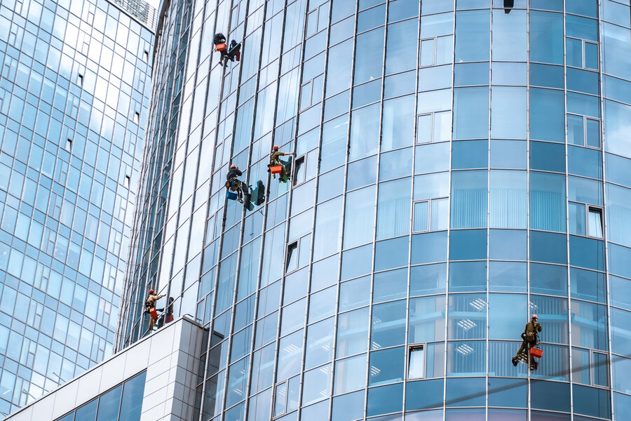 Several workers washing windows in the office building